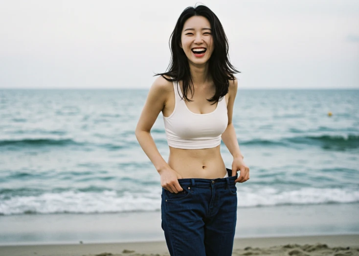 해변가에서 허리가 헐렁해진 바지를 잡고 환하게 웃는 한국 여성